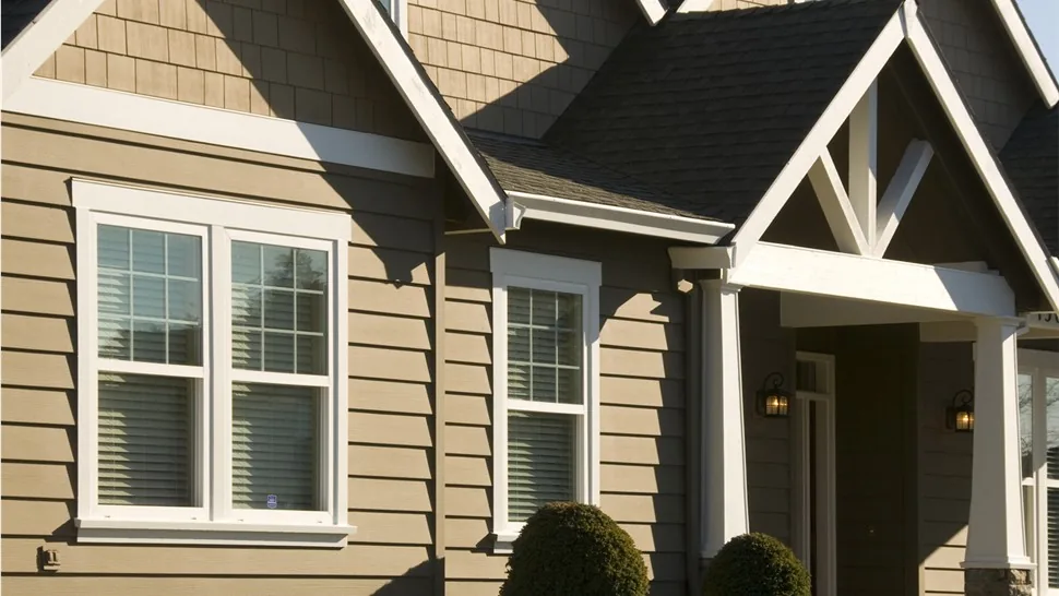 White Vytex vinyl double-hung windows on a home with tan lap siding