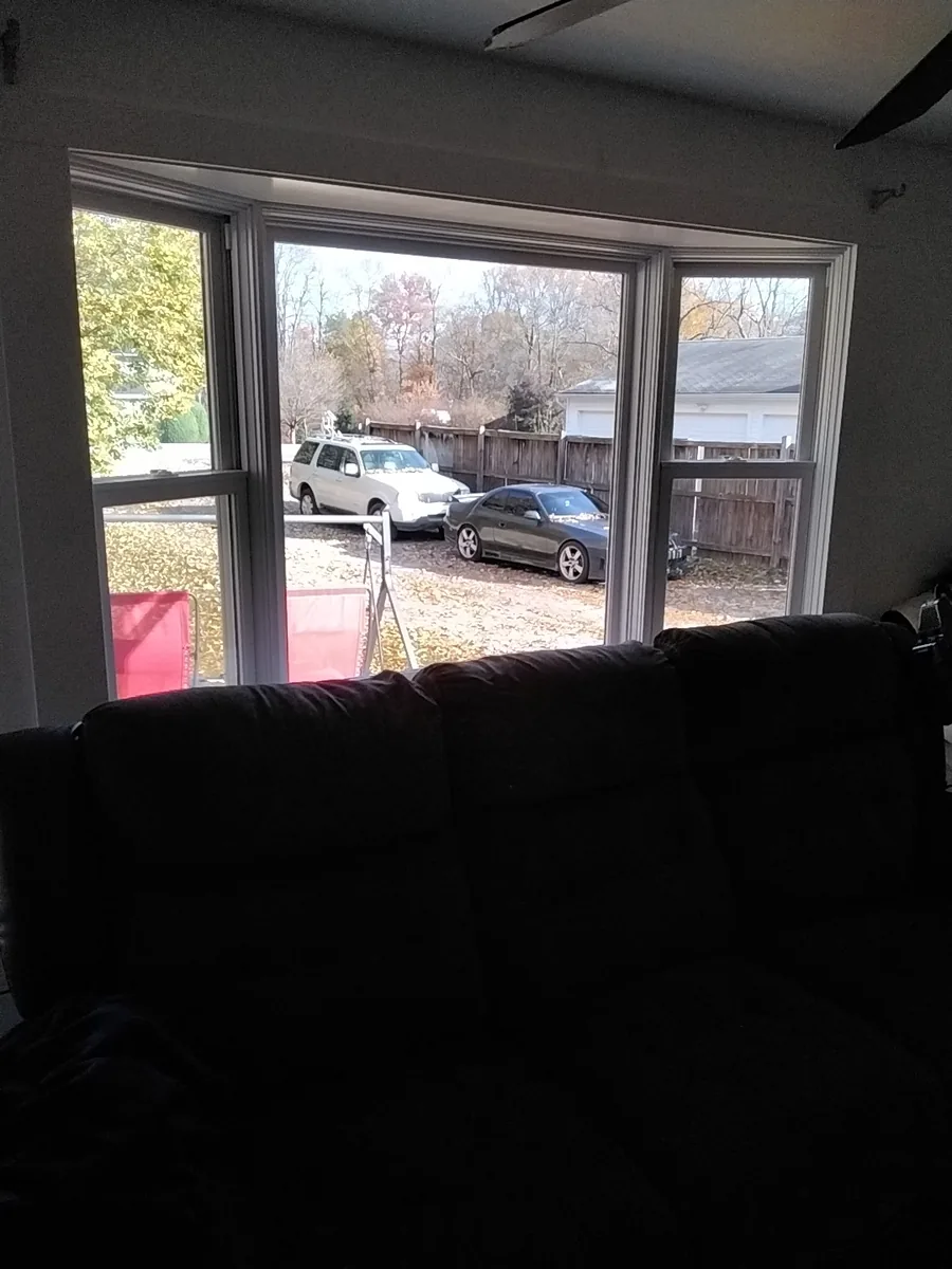 A new white bay window seen from inside a living room, looking out at the driveway