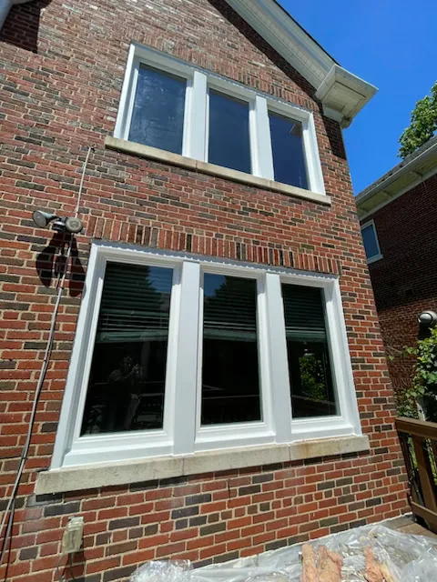 Two runs of new white casement windows in a red brick wall, one above the other