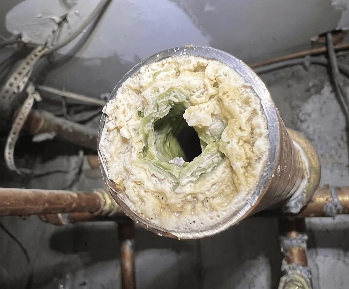 A cut section of household pipe almost closed off by built-up mineral scale